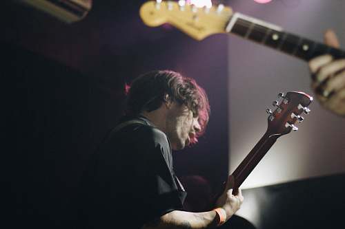 guitar man wearing black shirt standing while playing guitar electric guitar
